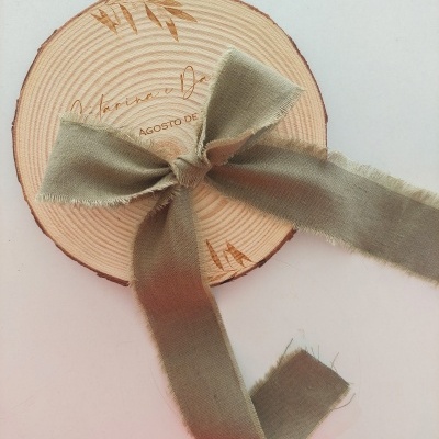 Disco de madeira com fita de tecido cinza amarrada em laço