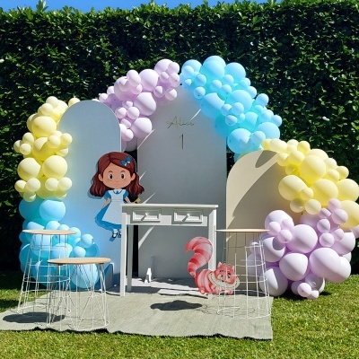 Cenário com balões coloridos, painel decorativo com nome e número, mesa e banquetas para festa infantil