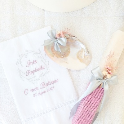 Conjunto de Batismo com toalha branca bordada, concha decorada e vela com tecido rosa e fita cinza.
