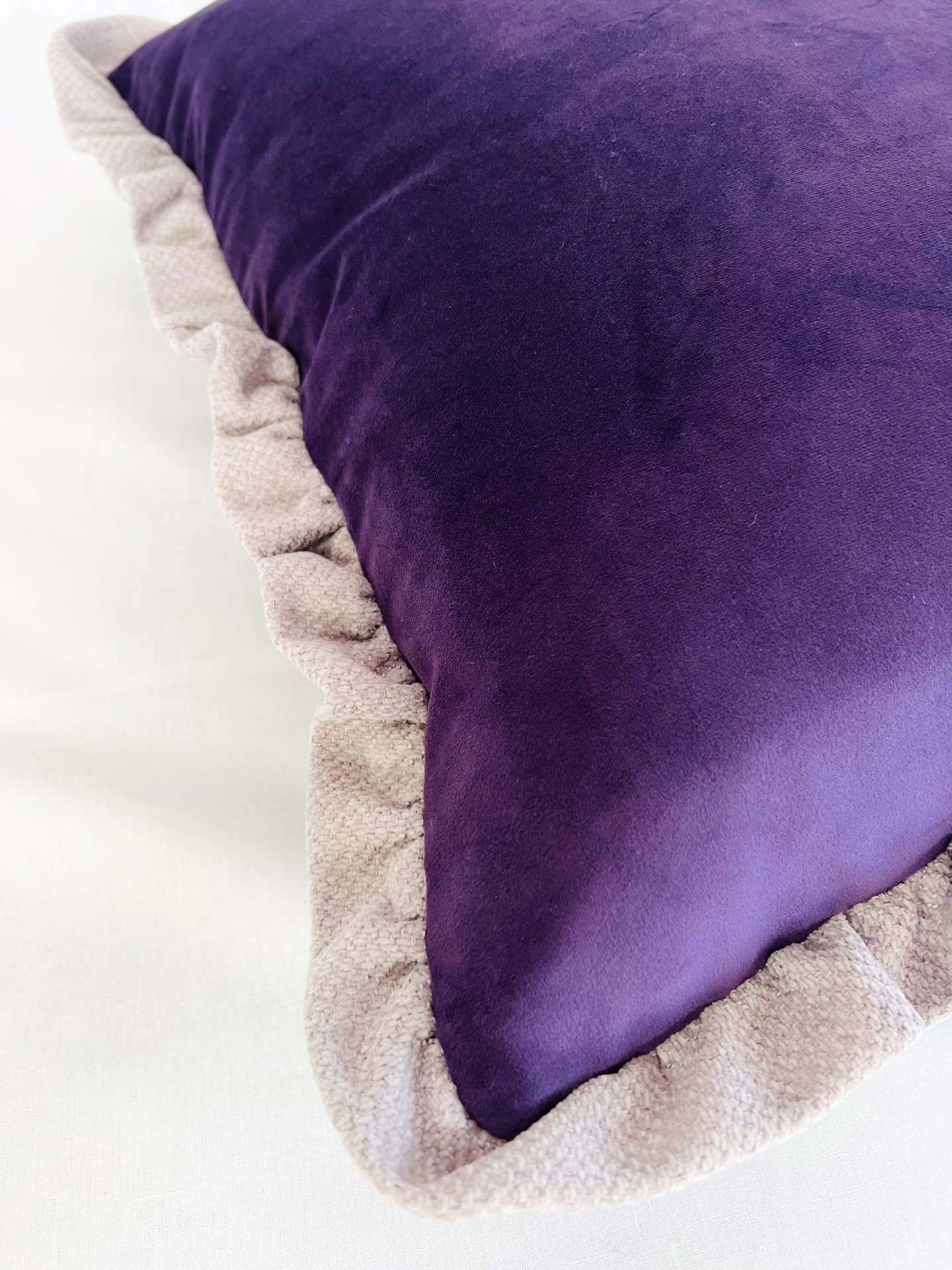 AL5050Ega Travesseiro roxo com borda franzida bege sobre superfície branca