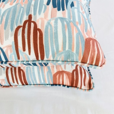 Almofadas coloridas com padrão abstrato empilhadas sobre superfície branca