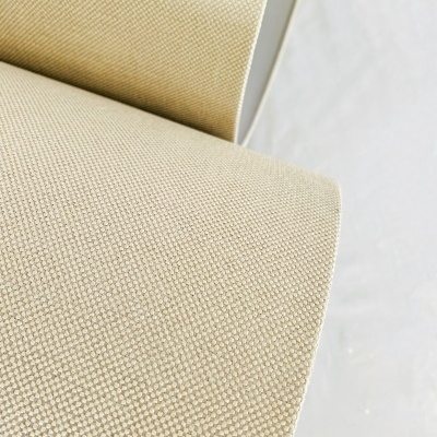 Tecido bege com padrão quadriculado e textura visível enrolado sobre superfície branca.