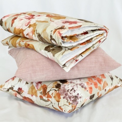 almofadas decorativas e edredão com padrão floral em tons terra