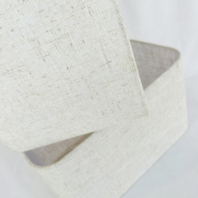 caixa retangular em tecido bege claro com textura linho e tampa levantada