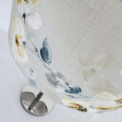 Abajur com cúpula de tecido floral bege e base metálica prateada