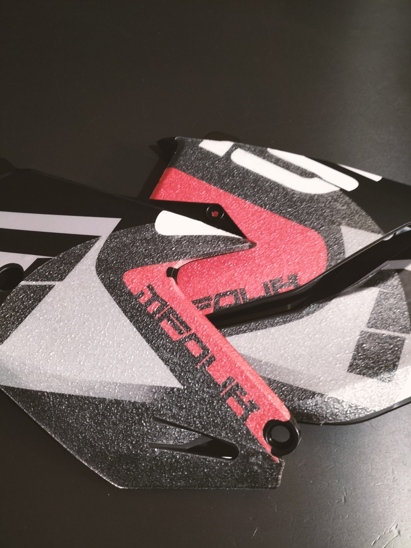 KIT ADESIVOS GRIP - GASGAS 2021 - 2023 Peça de plástico texturizada em preto, branco e vermelho com texto SPARK POWER, sobre fundo preto.