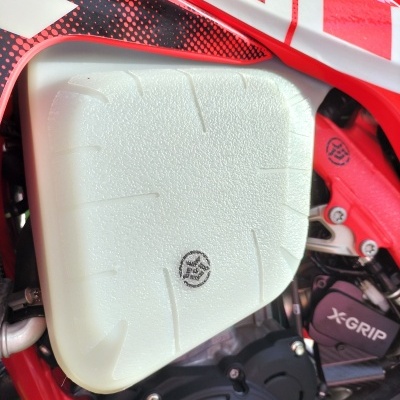 Tanque de combustível branco de mota com estrutura vermelha e texto X-GRIP