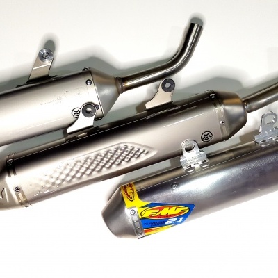 Três escapes de moto metálicos com tubos curvos sobre fundo branco.