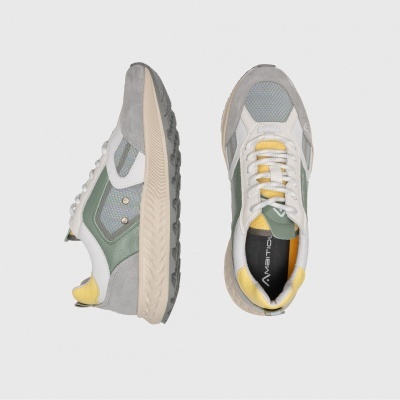 Par de sapatilhas casuais cinzentas, verdes e amarelas sobre fundo cinzento claro