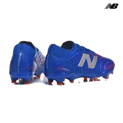 Chuteiras de futebol New Balance Tekela azuis com detalhes vermelhos e sola com cravos