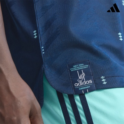 Camisola Adidas azul escura com etiqueta preta e calças verdes água com riscas pretas.