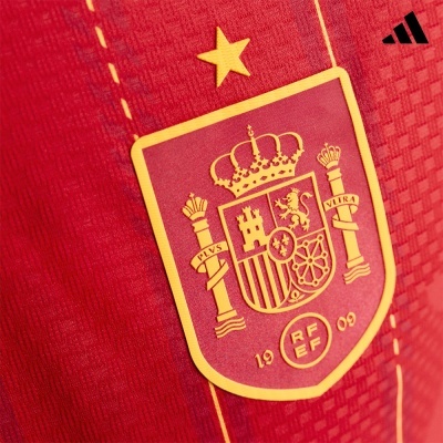 Emblema da seleção espanhola em tecido vermelho com detalhes amarelos.