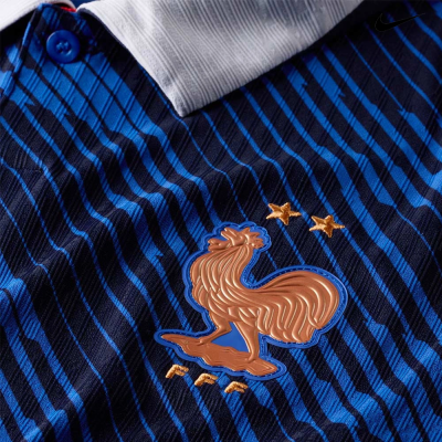 Camisola de futebol azul escura com riscas azuis, gola branca e botão azul, com emblema de galo castanho, duas estrelas e letras FFF.