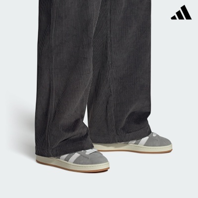 Calças de veludo cotelê cinza escuro com ténis Adidas cinza e branco.