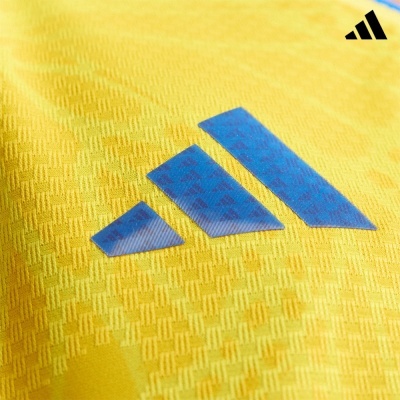 Tecido amarelo com padrão texturizado e logotipo Adidas azul