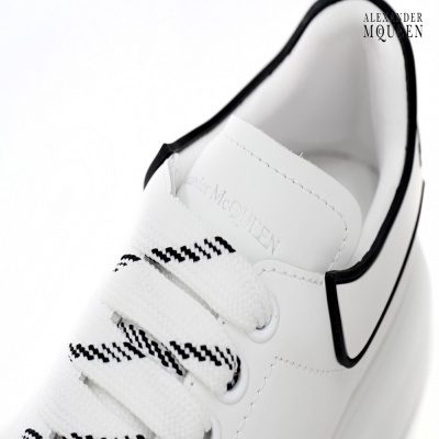 Vista de cima de ténis branco Alexander McQueen com cadarços brancos e pretos e detalhe preto no calcanhar