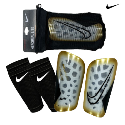 Caneleiras Nike Mercurial Lite brancas e douradas com protetores pretos e embalagem em rede
