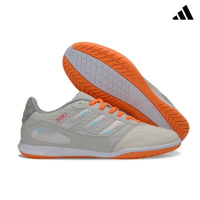 Sapatilhas Adidas Indoor cinza claro com atacadores laranja e sola laranja.