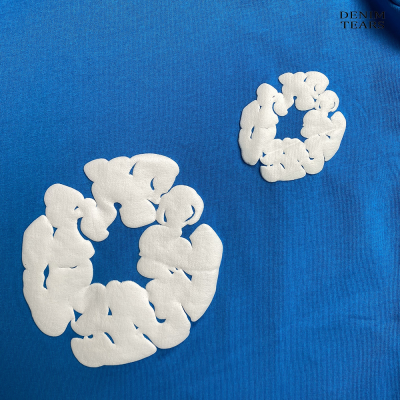 Detalhe de tecido azul com estampas brancas e texto DENIM TEARS