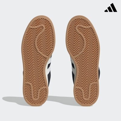 Solas castanhas de ténis Adidas sobre fundo cinza