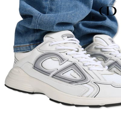 Tênis brancos com detalhes cinzentos e atacadores brancos usados com calças jeans azuis.