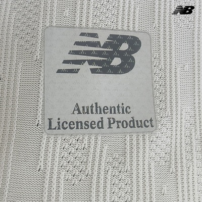 Etiqueta NB Authentic Licensed Product sobre tecido branco tricotado