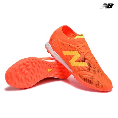 Sapatilhas de futebol laranja da New Balance com sola de pinos e logo amarelo