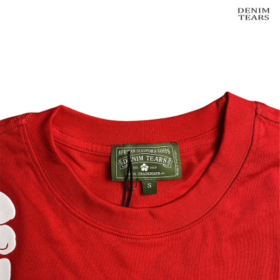T-shirt vermelha com etiqueta verde e texto DENIM TEARS no fundo branco