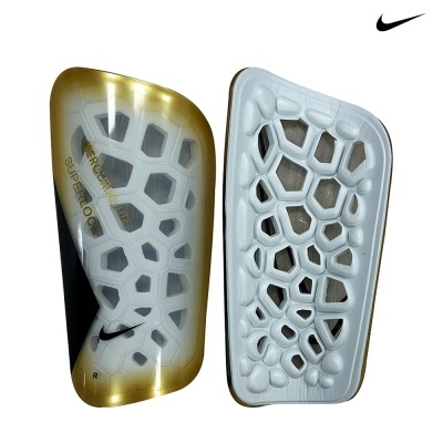 Caneleiras Nike Mercurial Lite Superlock brancas e douradas com padrão hexagonal