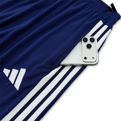 Calças desportivas azul com riscas brancas e telemóvel no bolso.