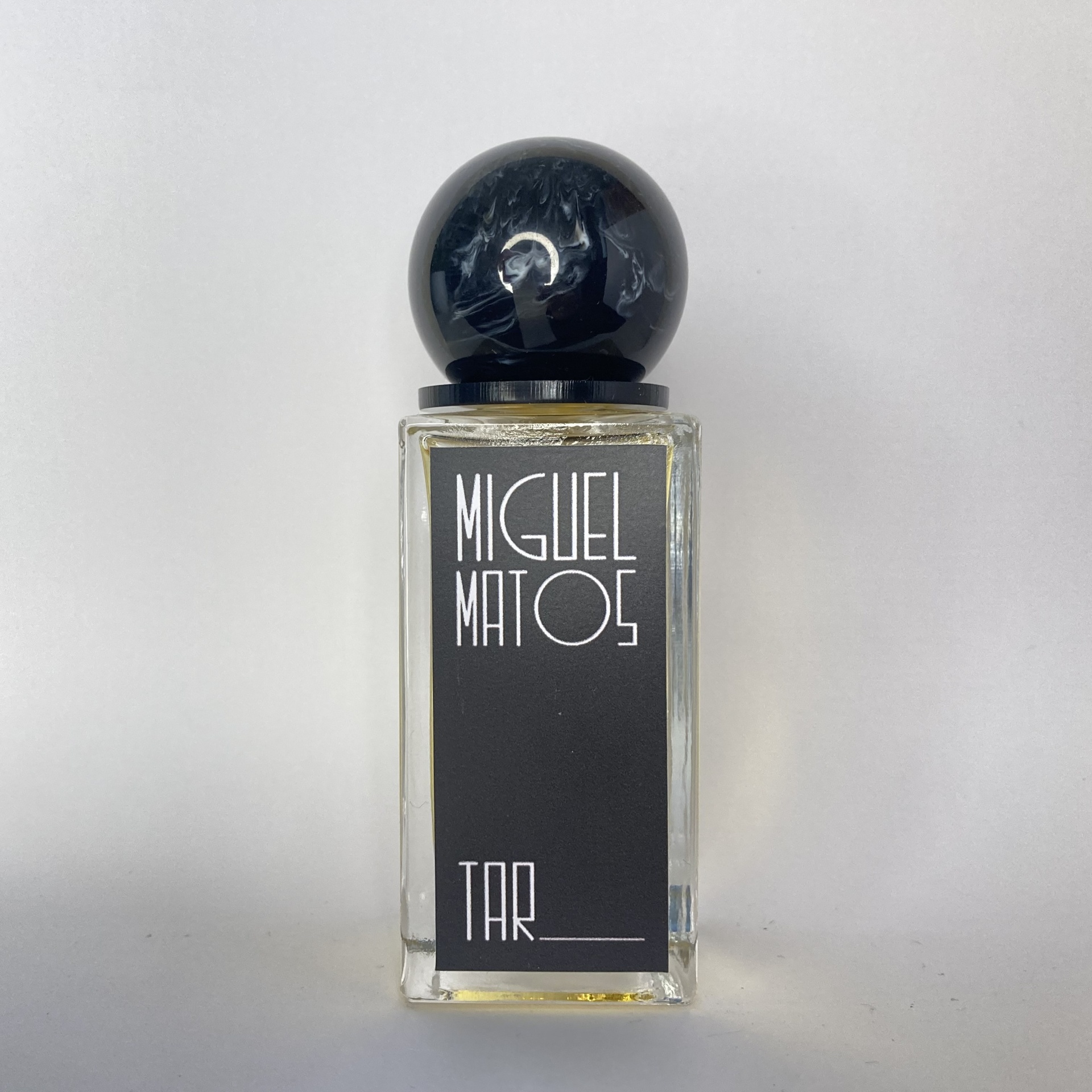 Frasco de perfume Miguel Matoes TAR com tampa preta e etiqueta preta