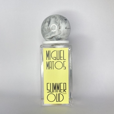 Frasco de perfume com rótulo amarelo e tampa marmoreada