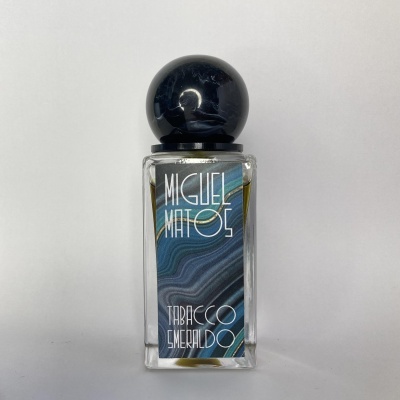 Frasco de perfume com tampa preta e etiqueta azul com texto