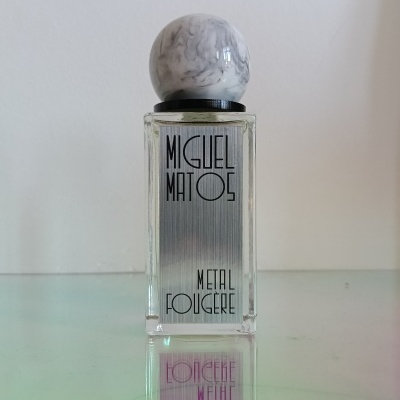 Clear glass perfume bottle with metallic label and marbled round cap