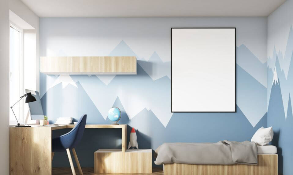 Quarto com parede azul e branca com montanhas, cama e mobília de madeira clara, cadeira azul escura