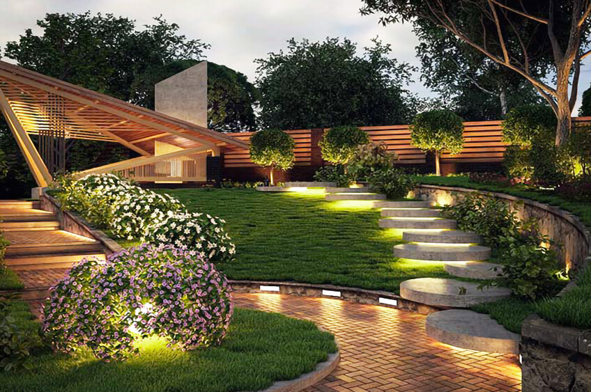 Jardim iluminado com escadas de pedra e arbustos floridos perto de uma casa moderna