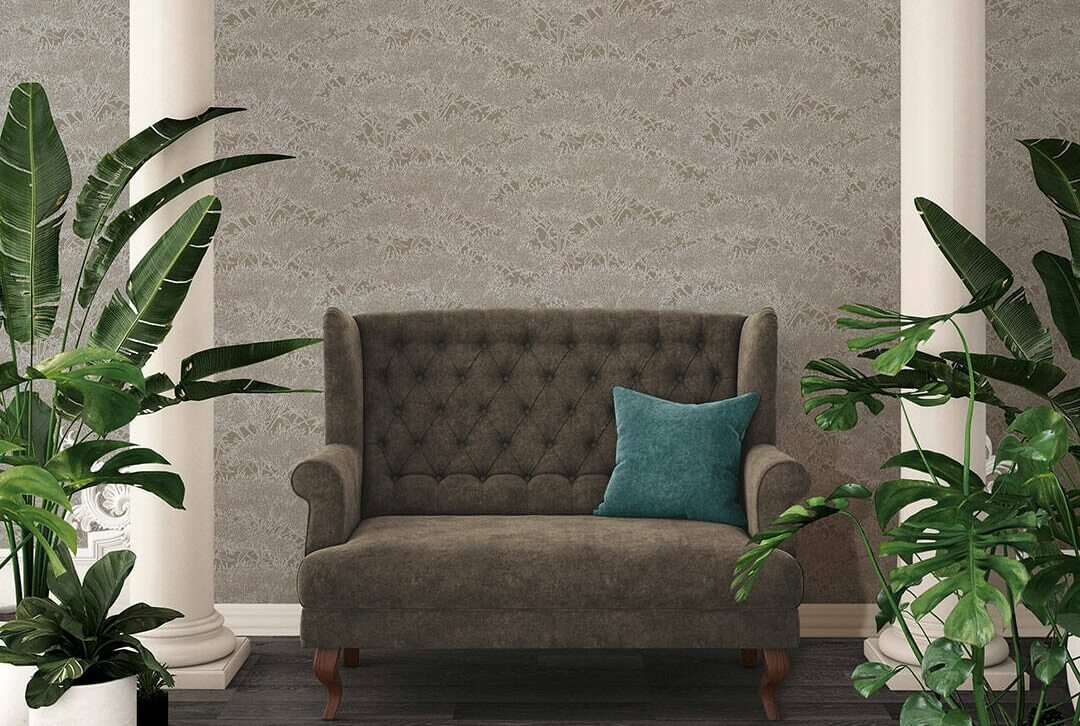 Papel de Parede Cinzento Absolutely Chic | 36972-1 Sofá castanho de dois lugares com almofada azul em sala com piso de madeira, paredes cinza texturas, colunas brancas e plantas verdes.