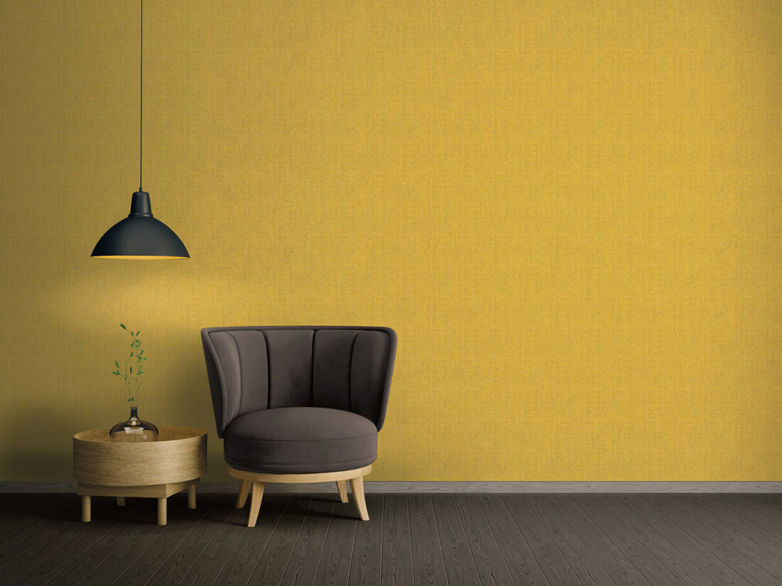 Papel de Parede Amarelo Mostarda Absolutely Chic | 36976-2 Cadeira cinzenta com mesa de madeira e candeeiro preto em frente a parede amarela