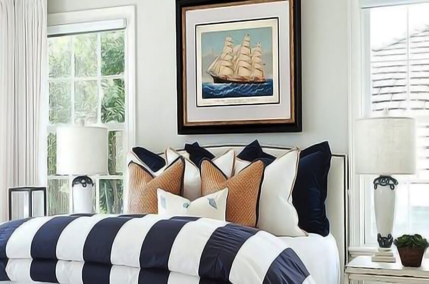 Cama com edredão às riscas azul e branco e almofadas decorativas