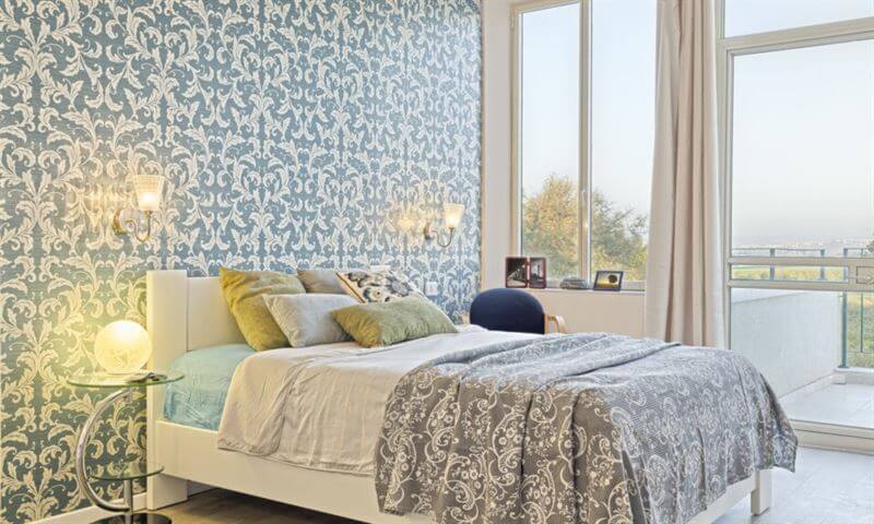 Quarto moderno com cama branca e papel de parede azul com padrão floral