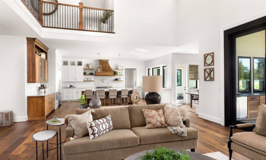 Sala de estar e cozinha integrada com sofá bege e móveis de cozinha brancos com madeira