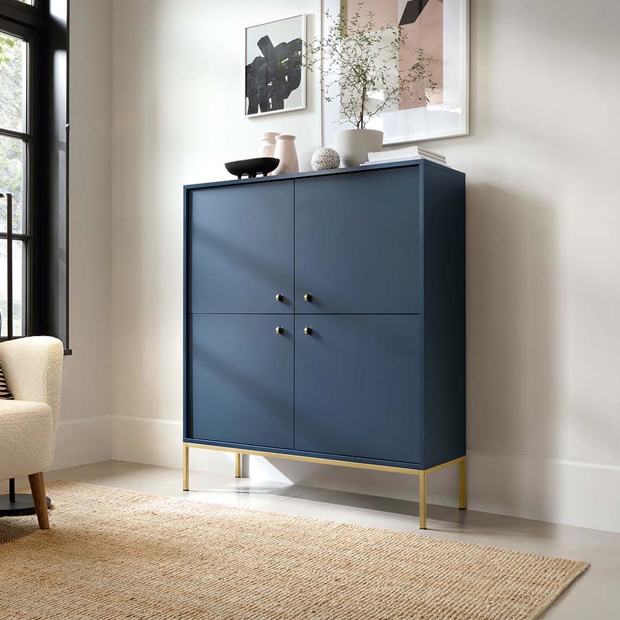Aparador Alto Azul Navi com Pernas em Dourado Mono Armário azul escuro com pernas douradas numa sala branca com carpete bege