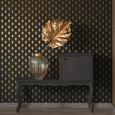 Aparador preto com vaso de vidro e folha dourada decorativa frente a parede com padrão de gotas douradas.