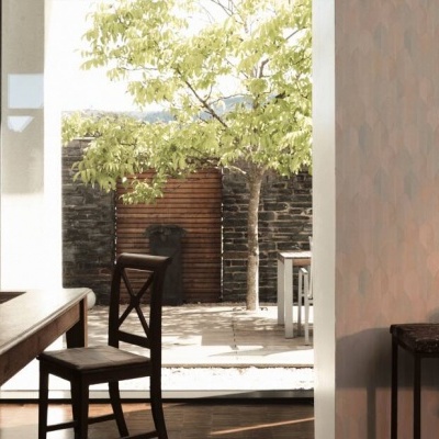 Sala de jantar com mesa e cadeiras de madeira junto a janela que mostra jardim exterior