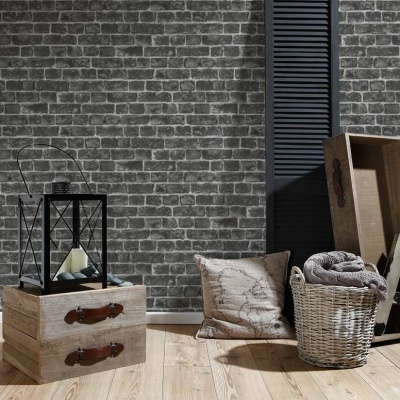 Decoração rústica com gavetas de madeira, lanterna, almofada, cesto com manta e caixa de madeira junto a parede de tijolos