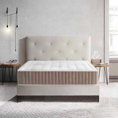 Cama estofada bege com colchão branco acolchoado em quarto minimalista com mesas de cabeceira redondas e candeeiros de parede