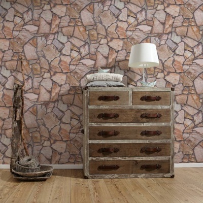Cómoda de madeira envelhecida junto a parede de papel pedra, com lâmpada branca e almofadas
