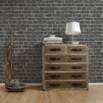 Cómoda rústica em madeira com cinco gavetas e puxadores em couro, com escultura de madeira e lâmpada branca num ambiente de chão de madeira e parede de tijolos escuros