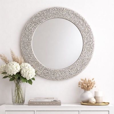 Espelho redondo com moldura texturada e decoração de flores brancas e velas em móvel branco