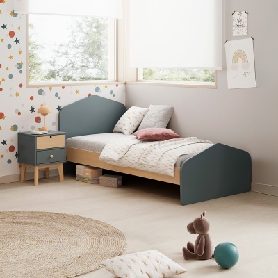 Quarto infantil com cama azul-escura, mesa de cabeceira, parede com estrelas coloridas e brinquedos no chão